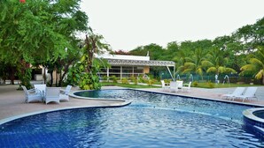 A swimming pool with lounge chairs and a building in the background. - Hotel Villaoeste (Mossoro)