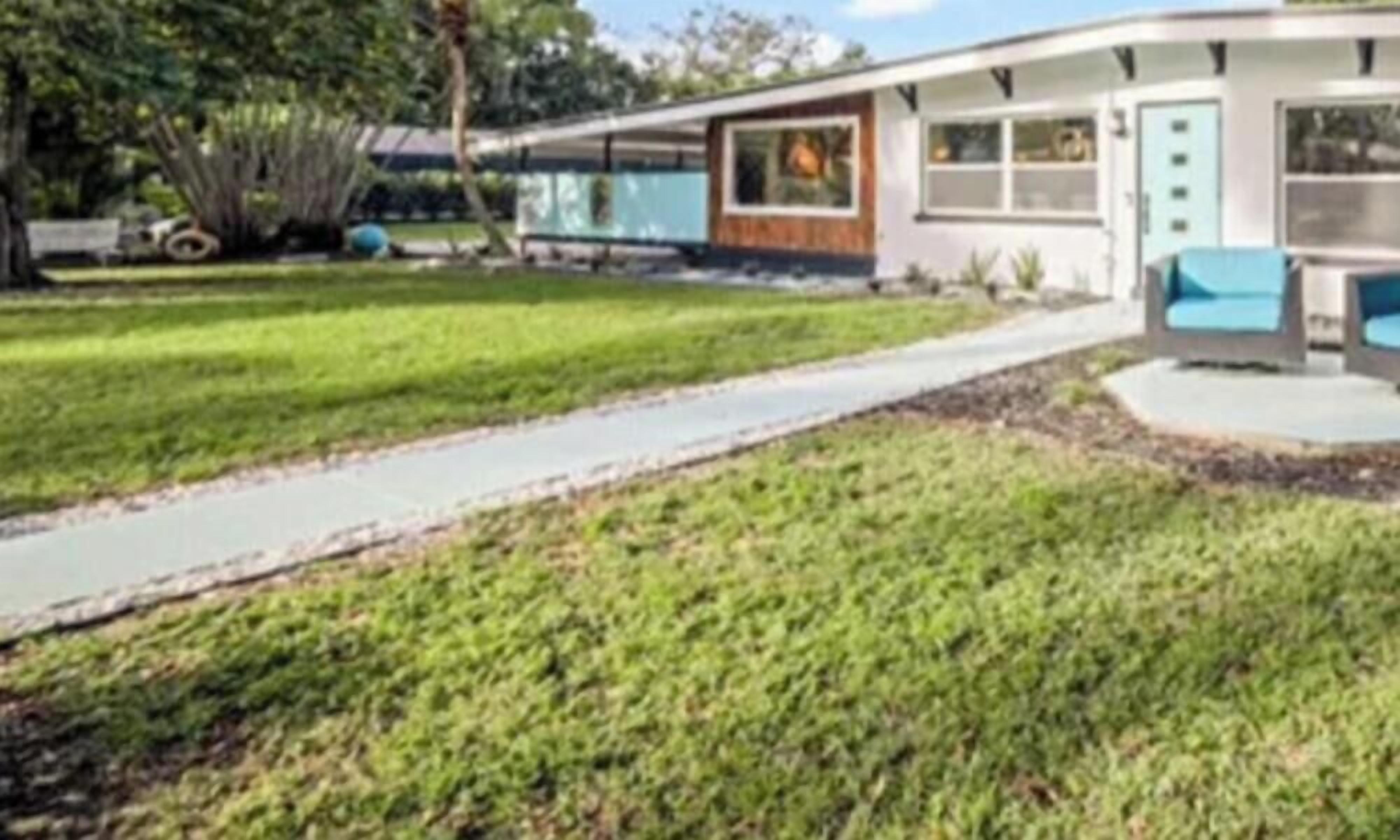 Une maison moderne avec un toit incurvé, un garage apparent et une pelouse bien entretenue.
