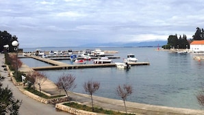 A marina with boats docked, a stone pathway, and a view of the water and distant mountains. - Spacious Holiday House Domenico (Preko)