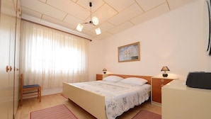 A bedroom with a bed, two bedside tables, a chair, a desk, a painting on the wall, and a window with curtains. - Spacious Holiday House Domenico (Preko)