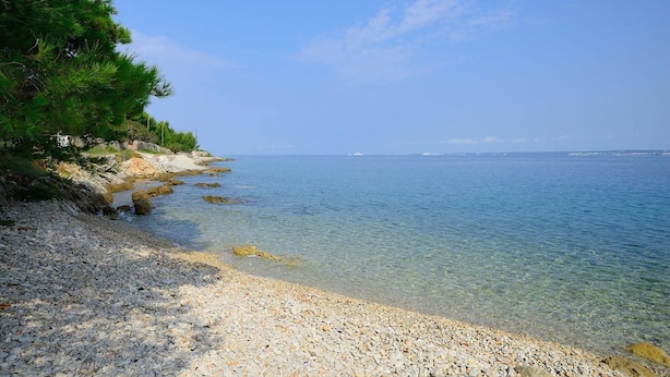 A pebble beach with clear water and a distant view of the sea. - Spacious Holiday House Domenico (Preko)