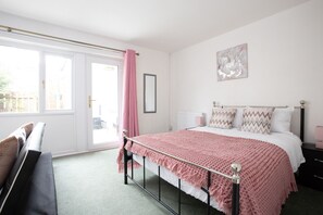 A bedroom with a bed, a bench, a window with a curtain, and a wall-mounted picture. - Hurley House (Cheadle)