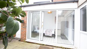A white room with a bed, a small table, and a window. - Hurley House (Cheadle)
