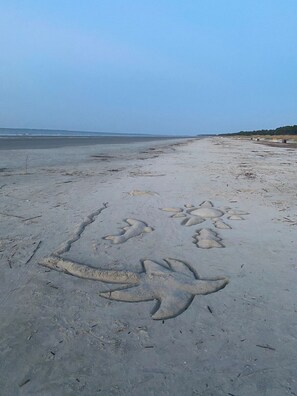 A beach with footprints and a dolphin drawing in the sand. - Hilton Head · Beautiful Hilton Head Condo across from the beach! (Hilton Head)