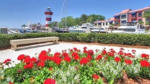 Un puerto deportivo con barcos, un faro y un edificio de techos rojos y azules.