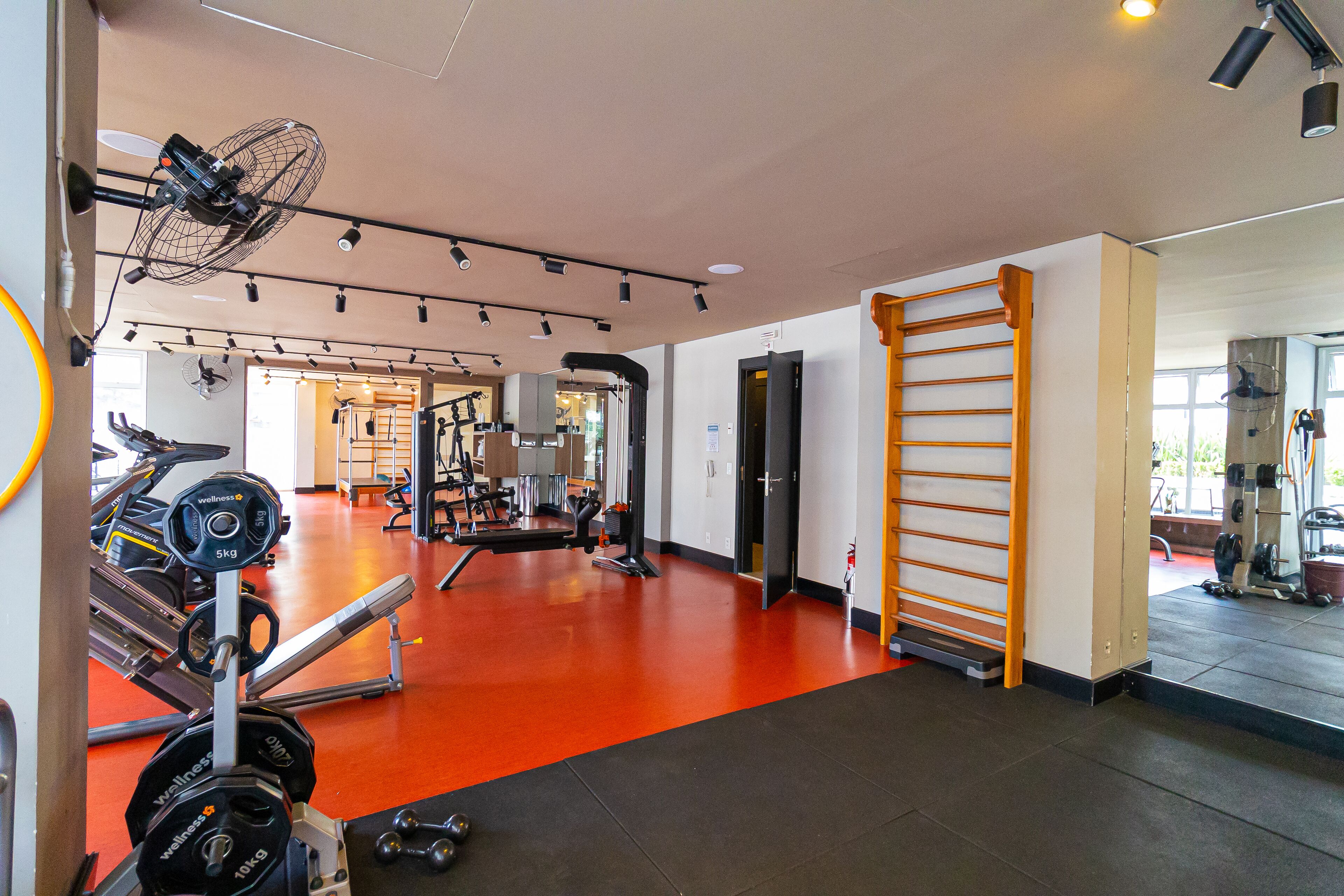 A gym with weightlifting equipment, a treadmill, and a pull-up bar.