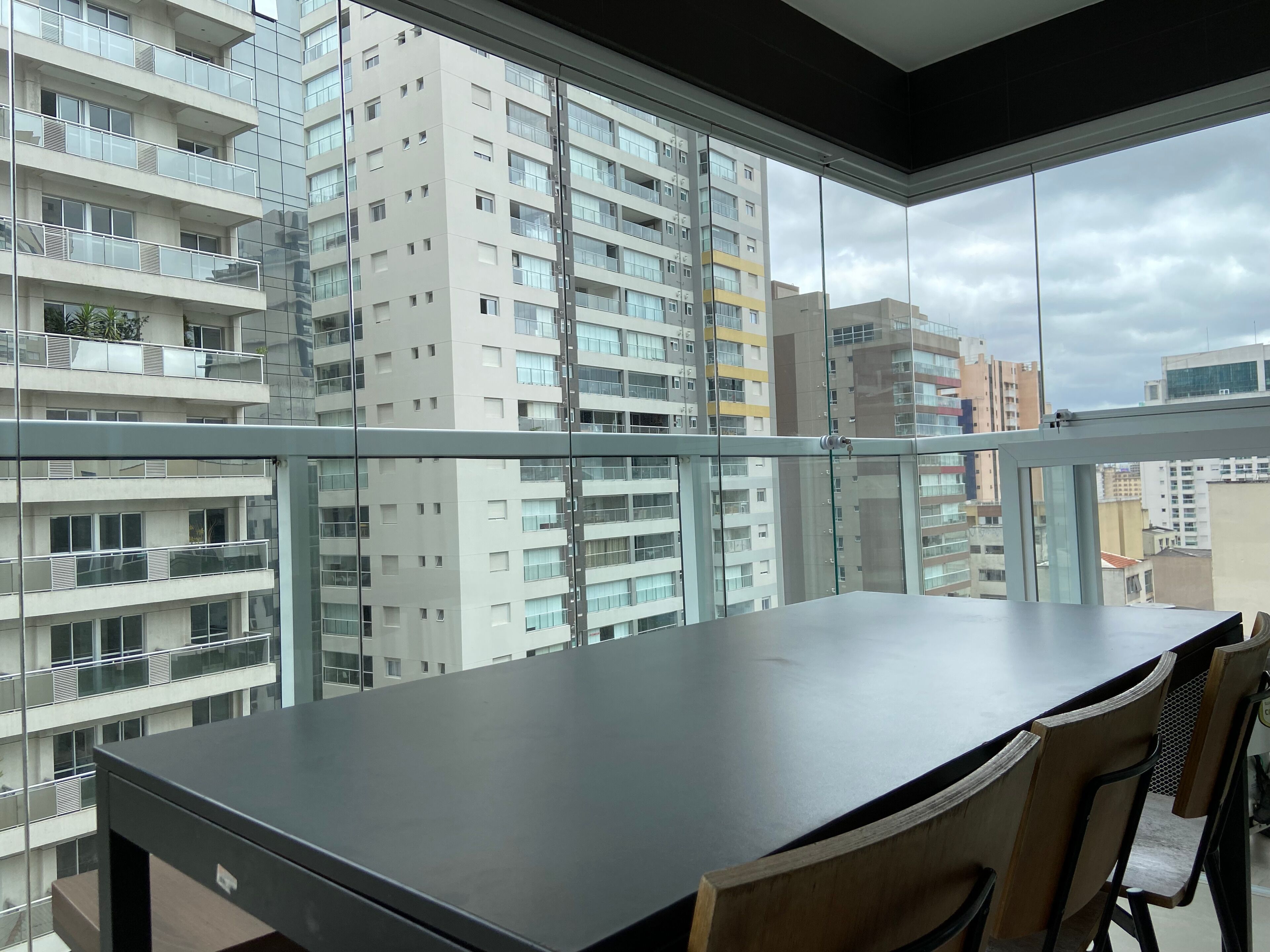 Un appartement moderne doté d’un balcon, de grandes fenêtres et offrant une vue sur les bâtiments environnants.