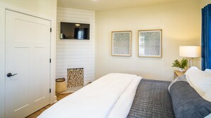 Una camera da letto con un letto, una ventola a soffitto, un comodino con una lampada e due opere d'arte appese alla parete.