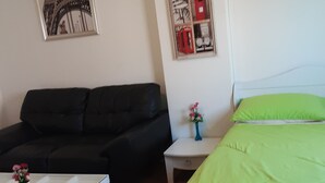A room with a bed, a sofa, a small table with a vase of flowers, and two framed pictures on the wall. - Room-t8@impact Challenger Mueang Thon Th (Pak Kret)