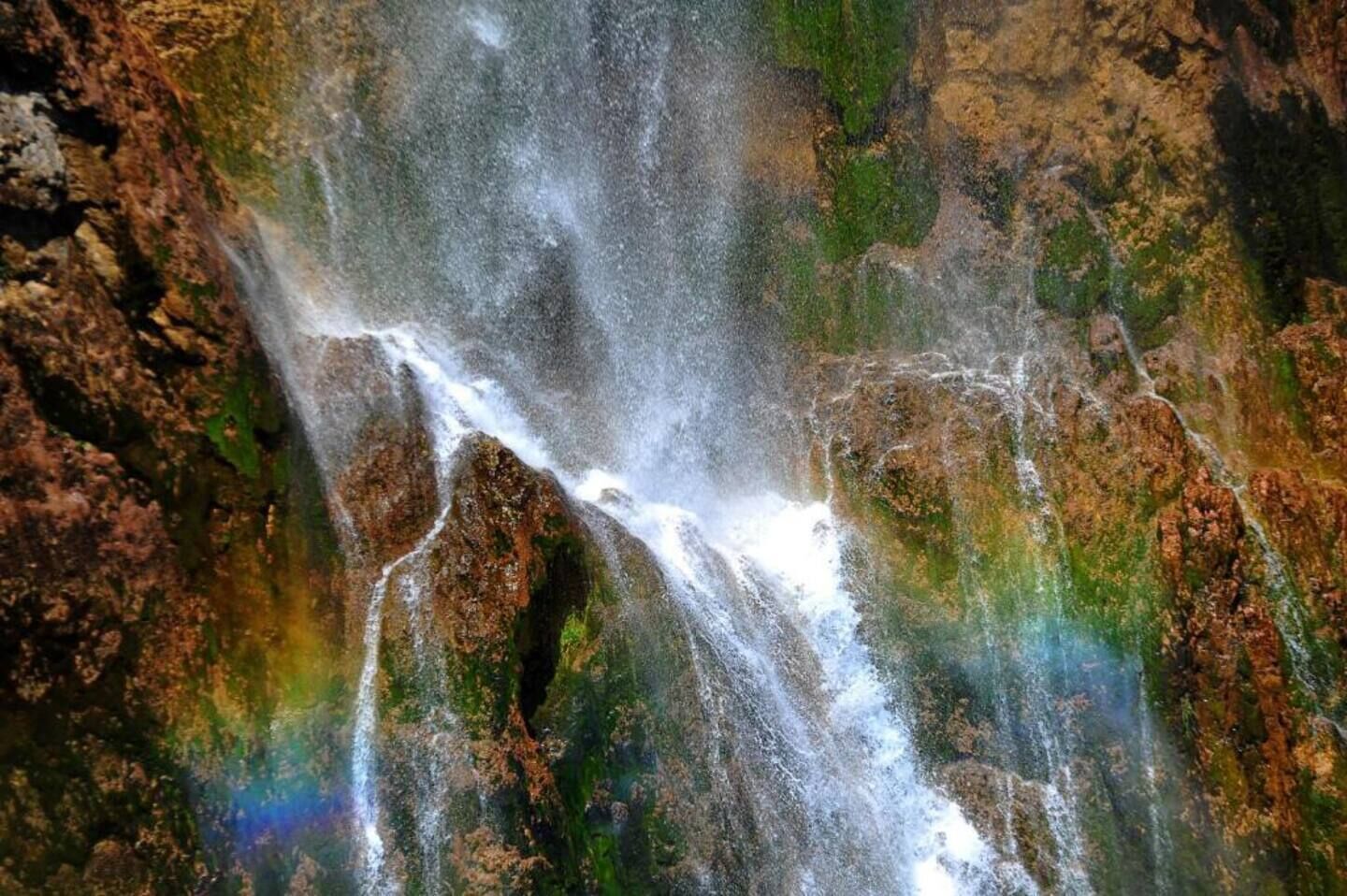 A waterfall cascading over rocky terrain with lush greenery.
