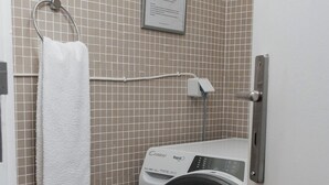 A laundry area with a washing machine, a towel rack with a white towel, and a sign on the wall.