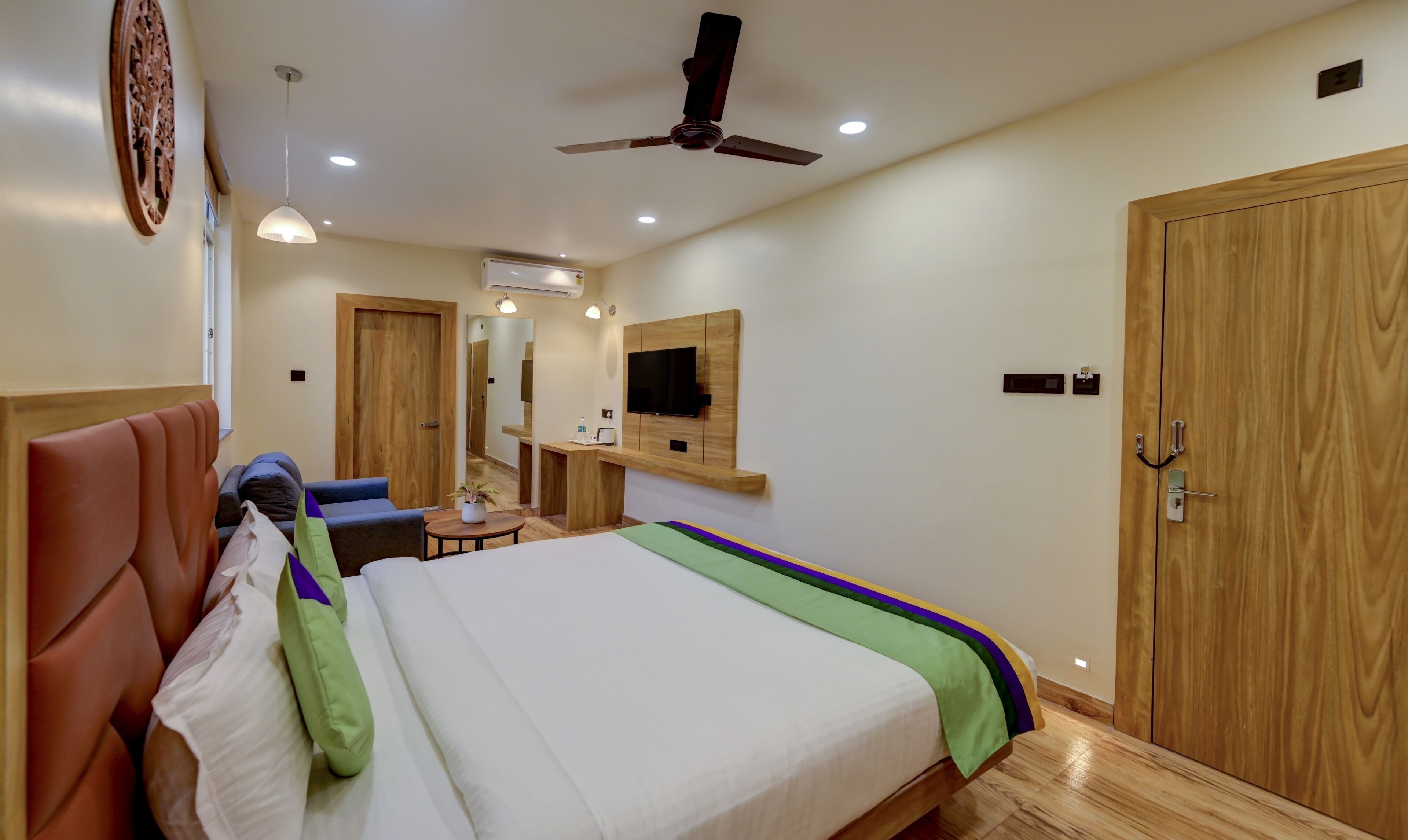 A hotel room with a bed, a desk, a chair, a television, and a wardrobe.