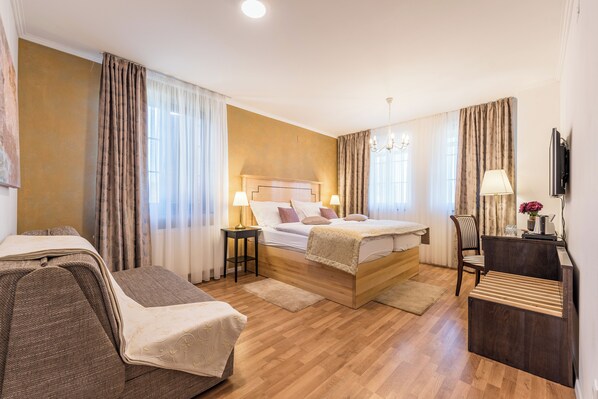 Habitación de hotel con cama de madera, un escritorio, una silla y un televisor.