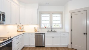 A modern kitchen with white cabinetry, a stainless steel dishwasher, and a built-in oven.