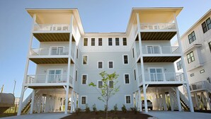 A multi-story residential building with balconies, a central garden, and a clear sky.