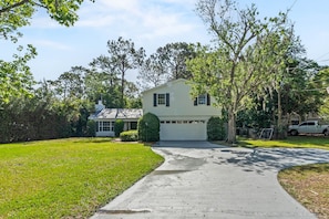 A single-story house with a garage, surrounded by a well-maintained lawn and mature trees.