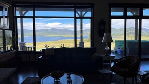 A living room with large windows offering a view of a lake and mountains. - Views, views, views!!!  Secluded setting over-looking beautiful Steamboat Lake. (Clark)