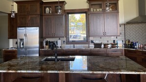A modern kitchen with dark wooden cabinets, a stainless steel refrigerator, granite countertops, and pendant lighting. - Views, views, views!!!  Secluded setting over-looking beautiful Steamboat Lake. (Clark)