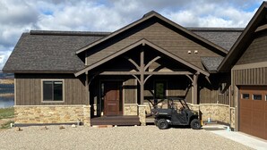 A modern house with a stone foundation, a wooden porch, and a garage. - Views, views, views!!!  Secluded setting over-looking beautiful Steamboat Lake. (Clark)