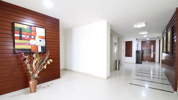 A modern hallway with a wooden panel wall, a colorful abstract painting, and a vase with dried flowers. - Best Western Tirupati Hotel (Tirupati)