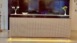 A modern reception desk with a sleek design, featuring a black countertop and vertical wooden slats. - Best Western Tirupati Hotel (Tirupati)