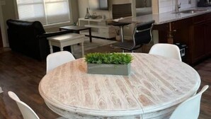 Een eetgedeelte met een ronde tafel, witte stoelen en een kroonluchter.
