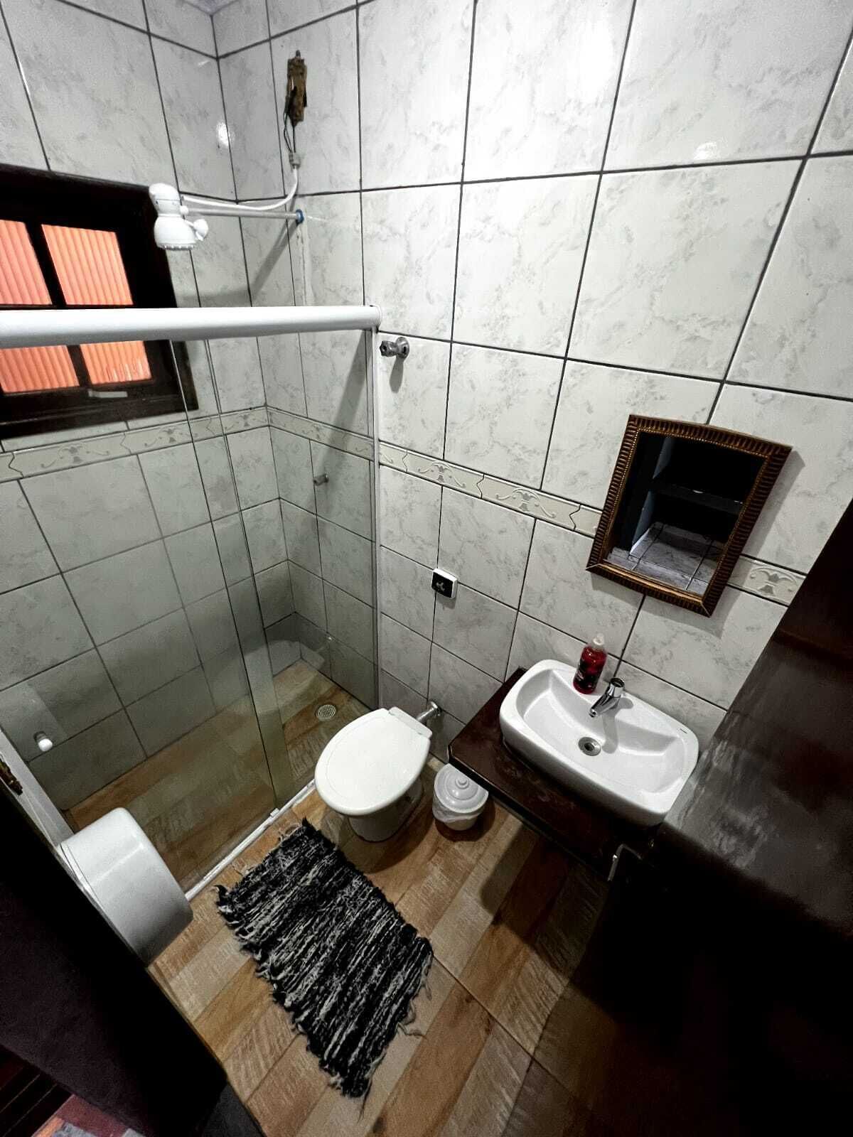 A bathroom with a glass shower enclosure, a toilet, a sink, and a mirror.