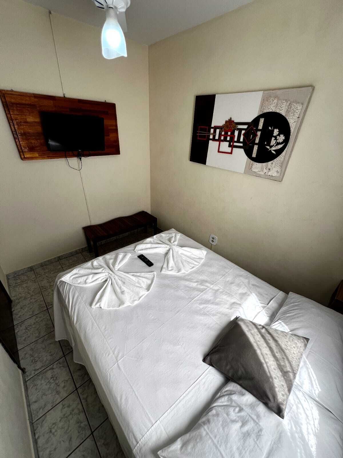 A bedroom with a bed, a TV mounted on the wall, and a decorative piece above the bed.