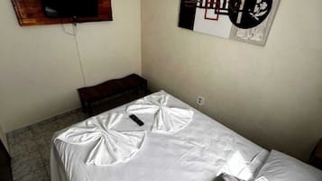 A bedroom with a bed, a TV mounted on the wall, and a decorative piece above the bed.