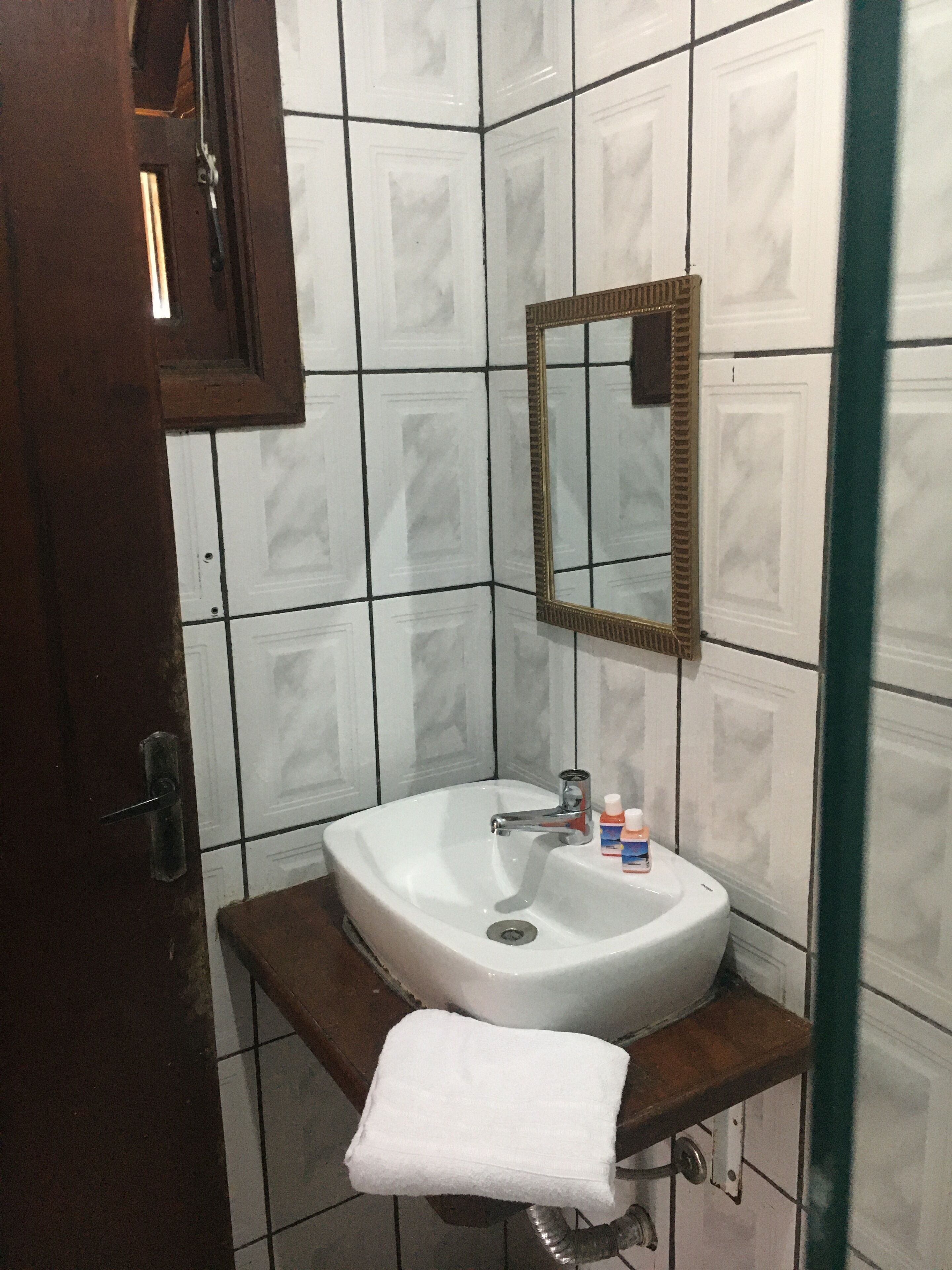 Une salle de bain avec un lavabo blanc, un miroir et une serviette posée sur un comptoir en bois.
