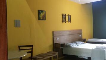 A room with a bed, a chair, a small table, and a ceiling fan.
