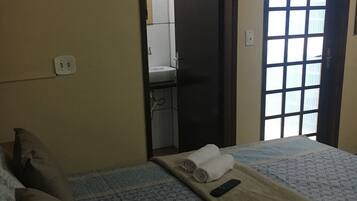 A hotel room with two beds, a bathroom visible through an open door, and a window with blinds.
