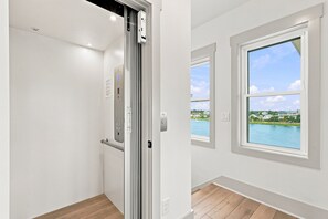 Une pièce avec vue sur un plan d’eau et des maisons, une porte coulissante et un interrupteur sur le mur.