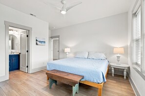 Ein Schlafzimmer mit einem Bett, Nachttischlampen, einer Bank und einem Deckenventilator.