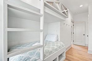 Ein Schlafzimmer mit Etagenbett, Einzelbett und einer Tür.
