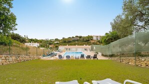 A pool area with lounge chairs and a stone wall. - Casa Amiga - Communal pool & garden, just 500m from beach (Carvoeiro)