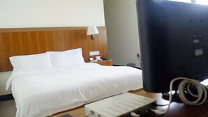 Una camera d'albergo con un letto, una lampada da comodino, una TV a schermo piatto e una scrivania con una tastiera.