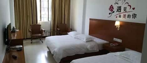 Habitación de hotel con dos camas, un escritorio, una silla, un televisor y una ventana con cortinas.