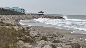 Una playa con terreno rocoso, un pabellón y un edificio con techos azules.