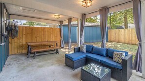 A covered patio with a wooden bench, a blue sofa, and a glass coffee table. - 3 miles from NAS * King and Queen Bed * Covered Patio * Luxury Bath * Open concept Living (Pensacola)