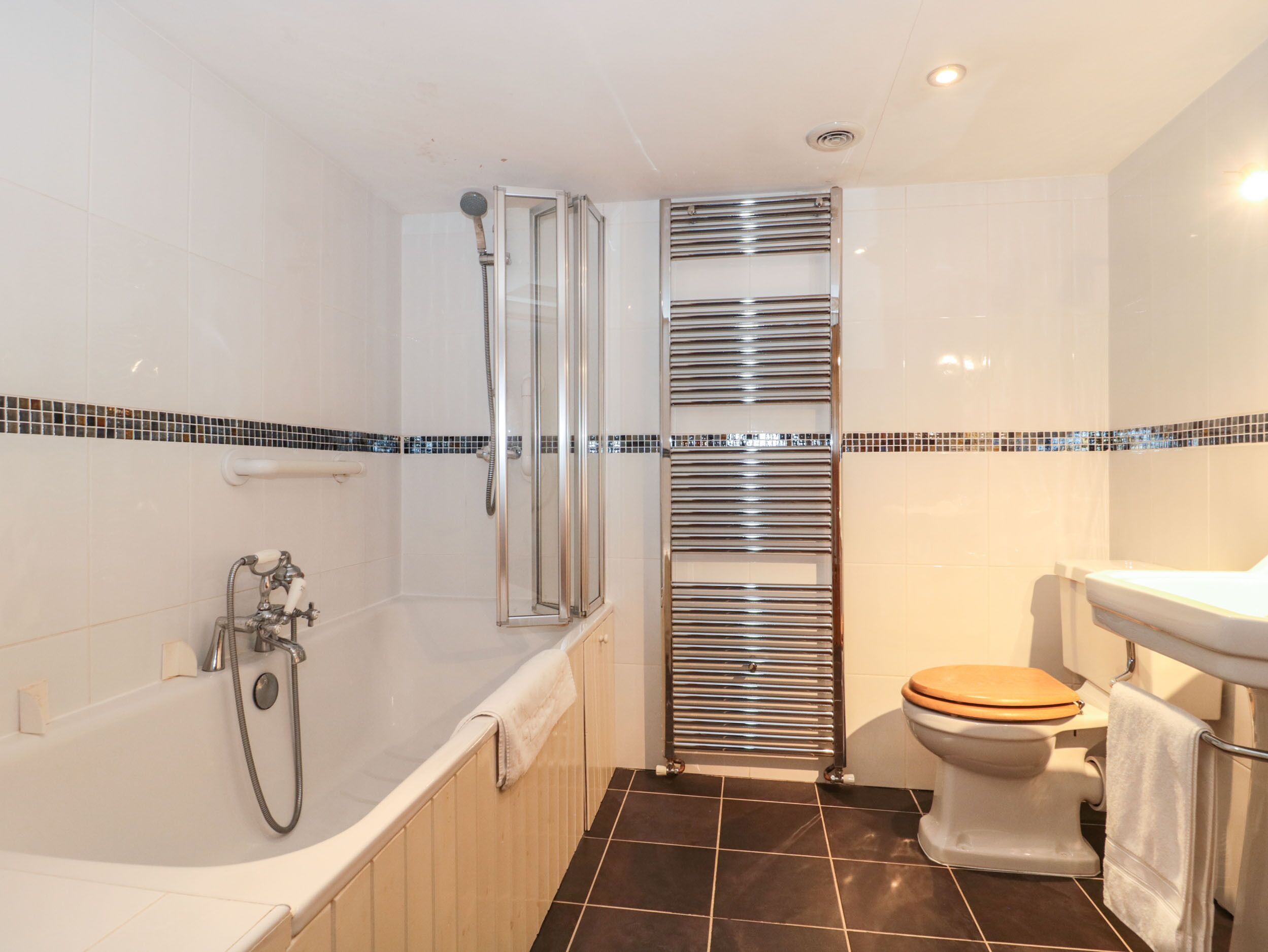 Une salle de bain moderne équipée d’une baignoire, d’une douche à parois de verre, de toilettes et d’un porte-serviettes.