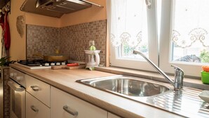 Una cocina con estufa a gas, un lavamanos y una ventana con cortinas decorativas.