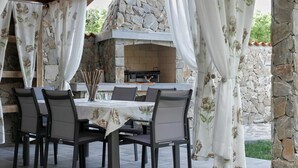 Un patio al aire libre con chimenea de piedra, una mesa con sillas y una parrilla.