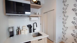 A modern kitchen with a built-in microwave, coffee maker, and tea maker. There are cabinets below the countertop and a sink with a faucet. - Studio4/Plateau/St-Denis/Terraces/SelfCheck-In/AC (Montréal)