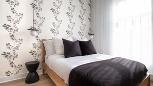 A bedroom with a wooden bed, white and black bedding, and floral wallpaper. - Studio4/Plateau/St-Denis/Terraces/SelfCheck-In/AC (Montréal)