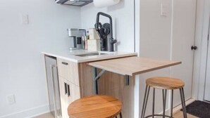 A compact kitchen with a wooden countertop, two stools, and a built-in oven. - Studio4/Plateau/St-Denis/Terraces/SelfCheck-In/AC (Montréal)