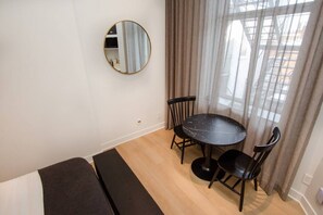 Une petite pièce avec une table ronde, deux chaises, un canapé et un miroir au mur.