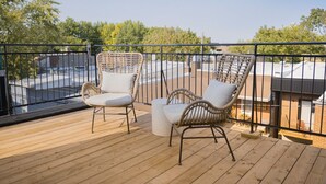 A wooden deck with two wicker chairs and a small table, overlooking a cityscape. - Studio13/Plateau/St-Denis/Terraces/SelfCheck-In/AC (Montréal)