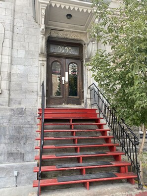 Une entrée d’immeuble avec un escalier rouge menant à une porte portant l’inscription « 3030 ».