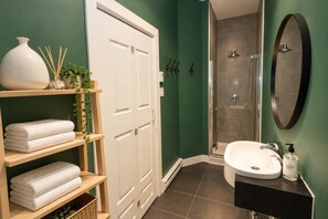 Une salle de bain avec un lavabo blanc, un miroir, une douche et une porte blanche.